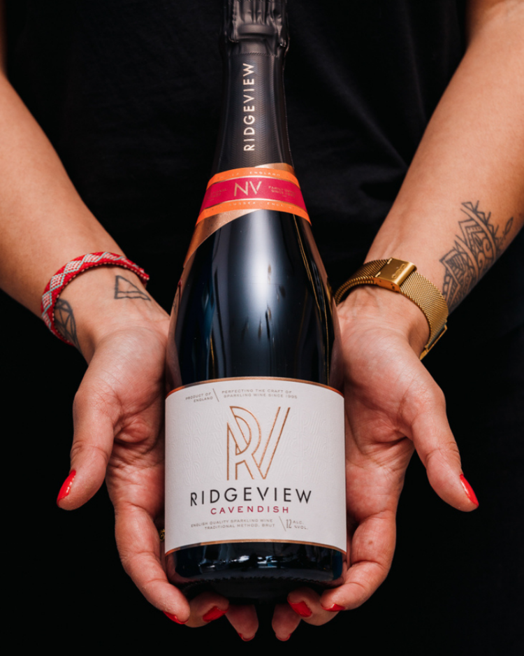 Ridgeview Wine Estate, English Sparkling Wine, Cavendish bottle held in hands with tattoos, watches and red nail varnish