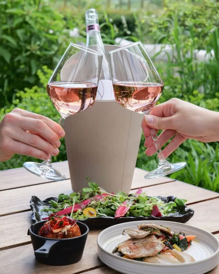 Ridgeview English Rosé Wine in glasses clinking surrounded by food at Ridgeview's vineyard restaurant, The Rows & Vine