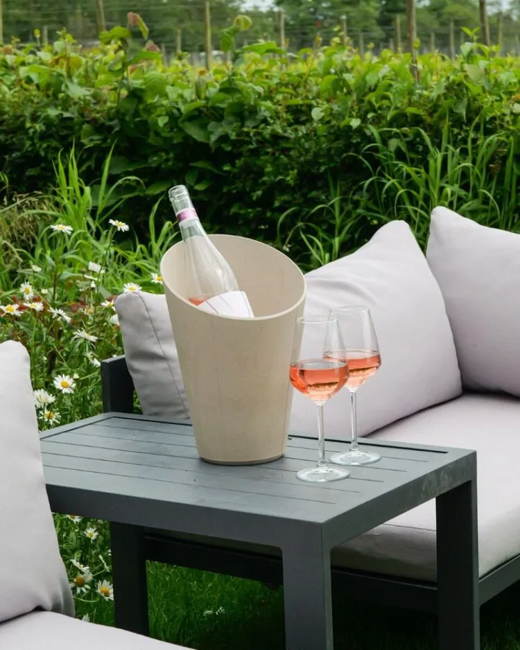 Ridgeview English Rosé Wine in an ice bucket with glasses next to it and surrounded by sun loungers and green scenery at the Ridgeview estate