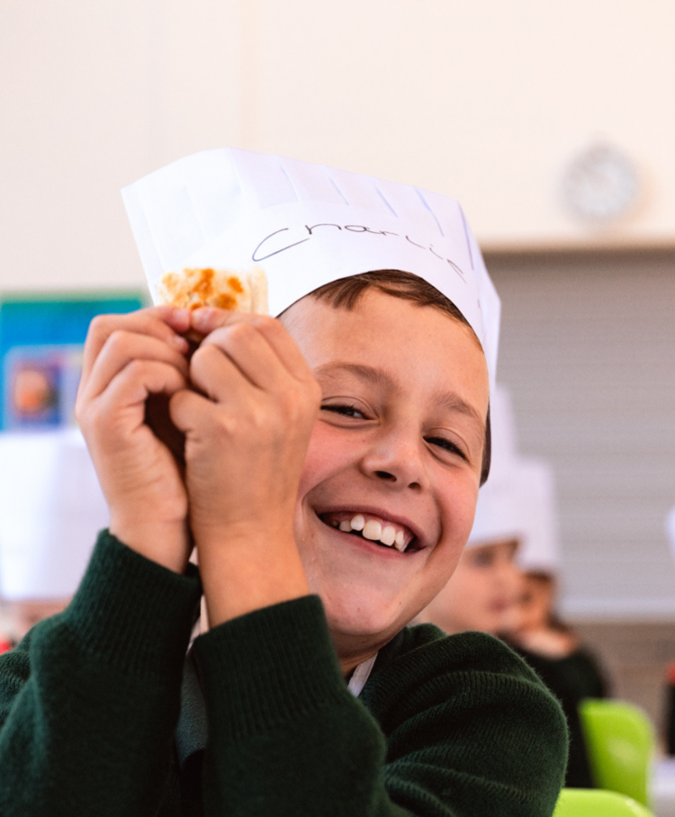A child holding up food and smiling