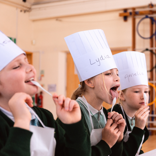 3 children wearing chefs hats and licking spoons